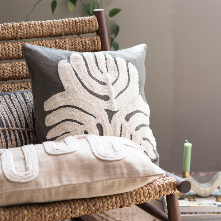 Decorative pillows with leaf patterns on a woven chair.