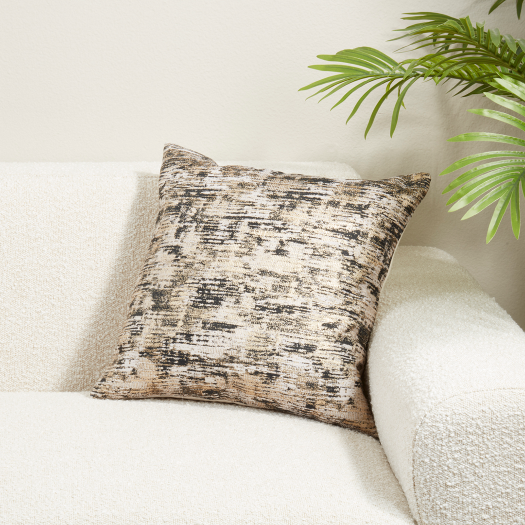 Textured throw pillow on a white couch with a plant in the background