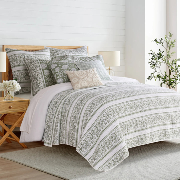 Bedroom with a bed featuring patterned bedding and pillows, wooden nightstands, and lamps.