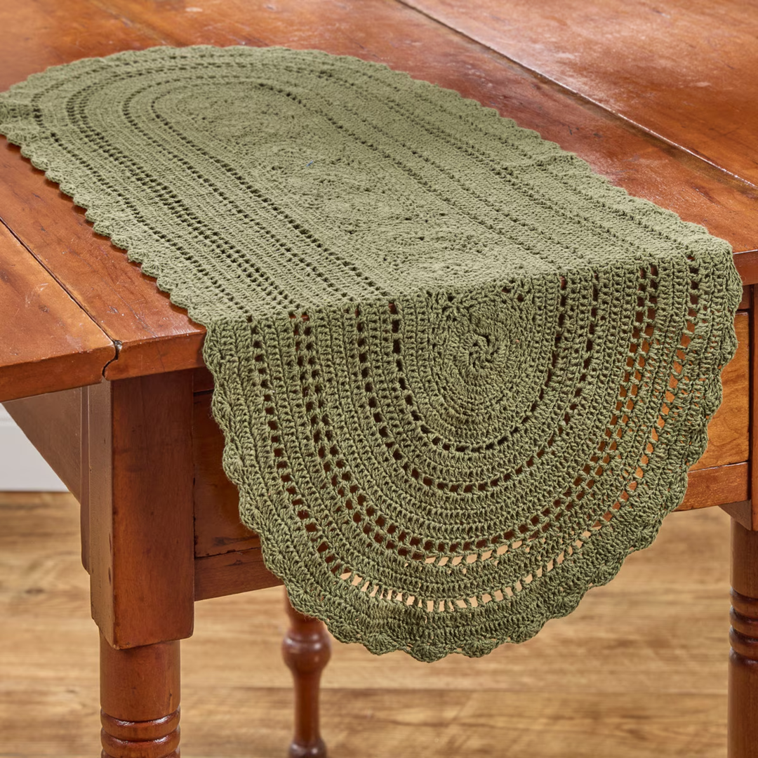 Green crocheted table runner on a wooden table