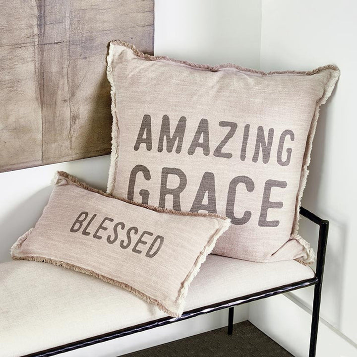 Two pillows with 'Amazing Grace' and 'Blessed' text on a white surface.