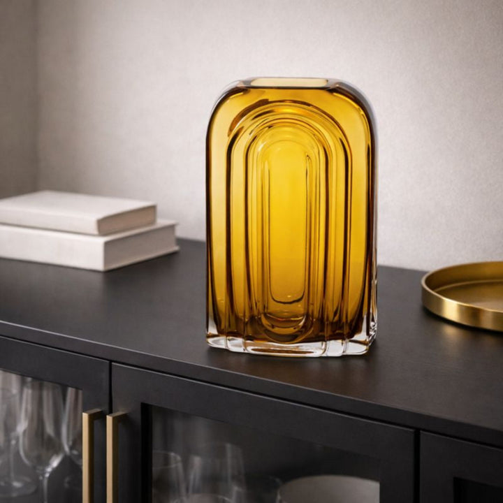 Yellow glass vase on a dark surface with a neutral background