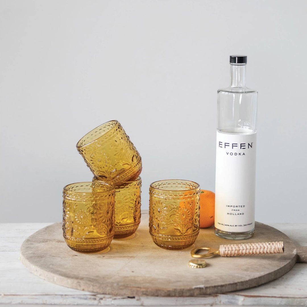 Amber Embossed Drinking Glass on round wooden tray with bottle opener and clear bottles