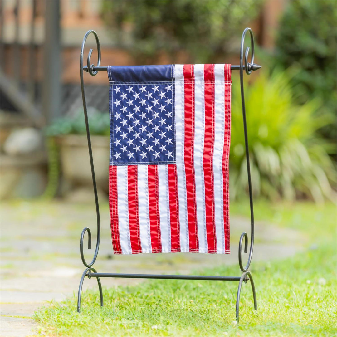 American flag on a decorative stand in a garden setting