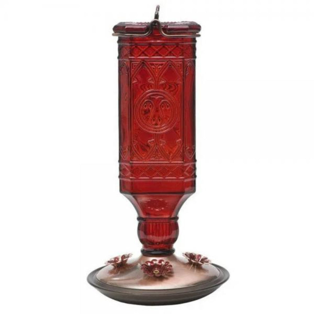 Red glass hummingbird feeder with intricate patterns on a white background