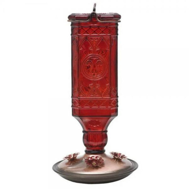 Red glass hummingbird feeder with intricate patterns on a white background
