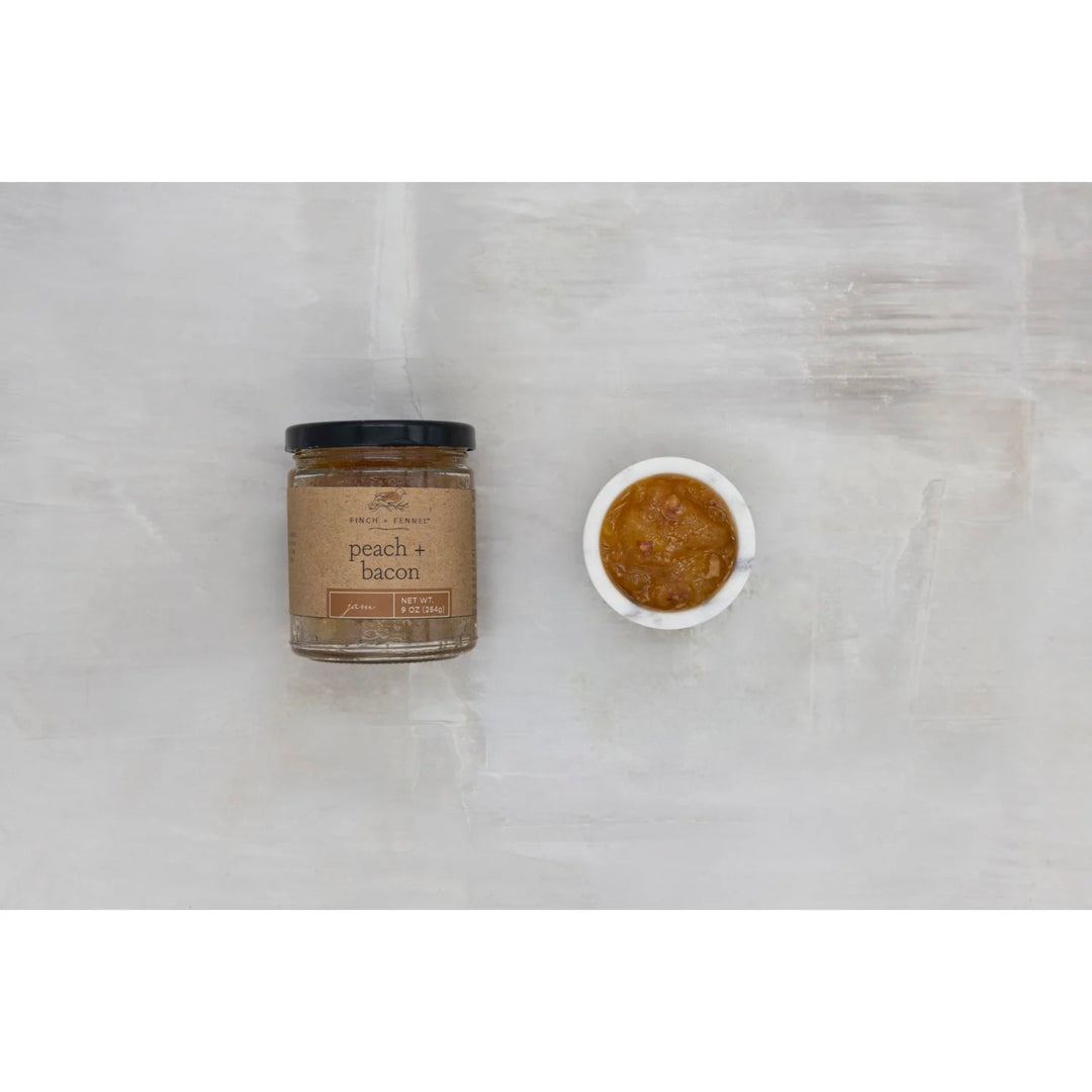 Jar of peach and bacon spread on a marble surface