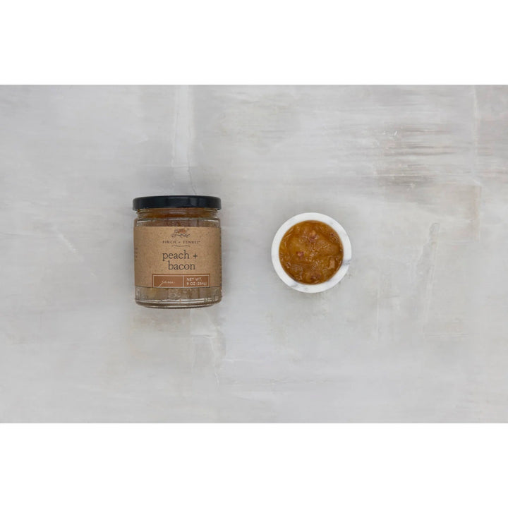 Jar of peach and bacon spread on a marble surface