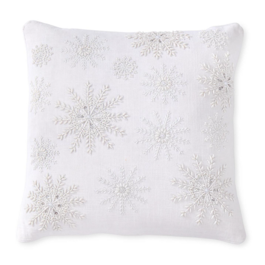 A square white throw pillow featuring large and small embroidered snowflakes in white and subtle silver thread, set against a plain white background.