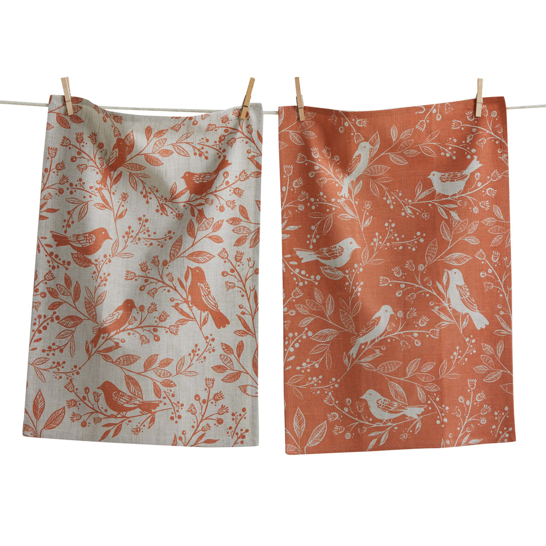 Two patterned towels hanging on a line with birds and floral designs.