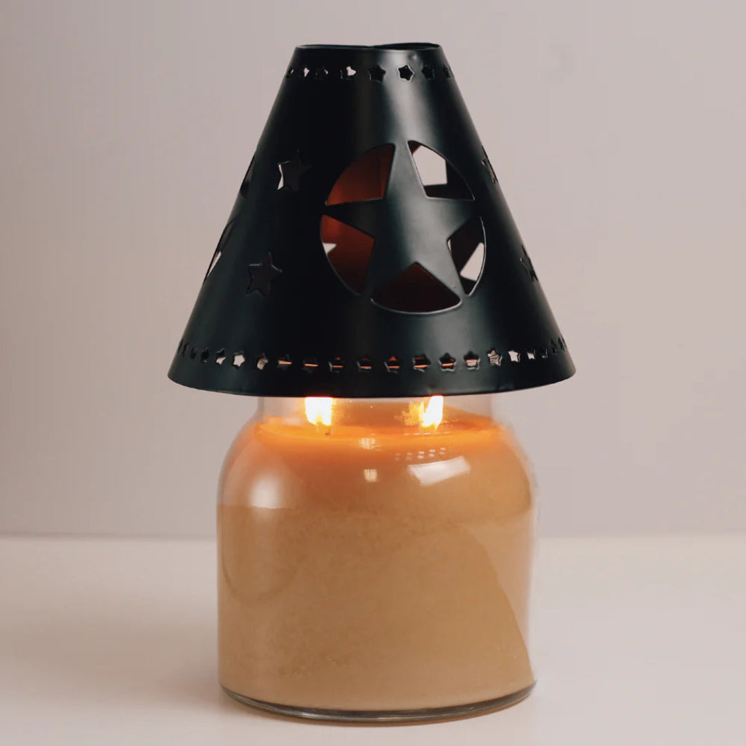 Candle lantern with black star-shaped cutout on a neutral background