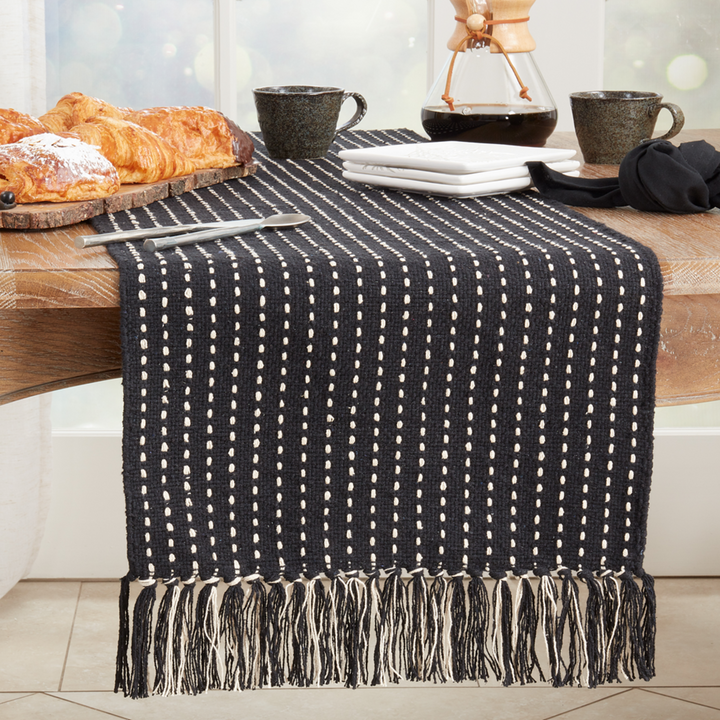 Black and white patterned table runner on a wooden table with croissants and coffee.