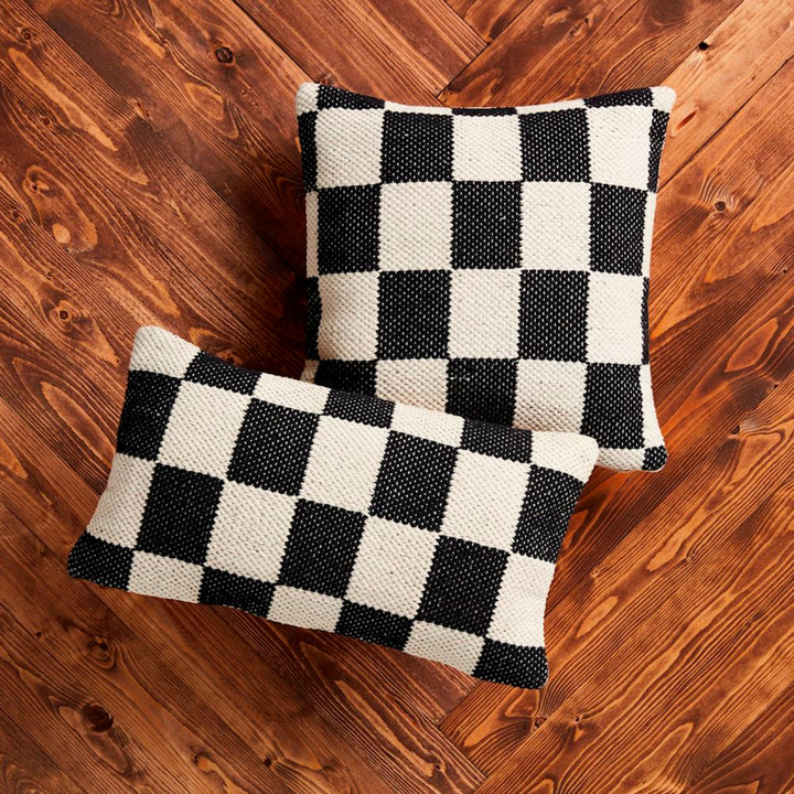 Two black and white checkered pillows on a wooden floor.