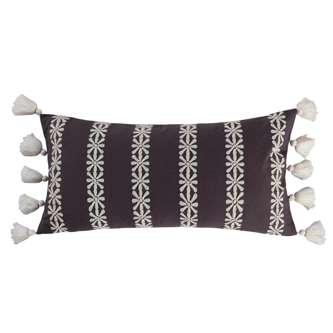 Decorative pillow with white patterns and tassels on a brown background