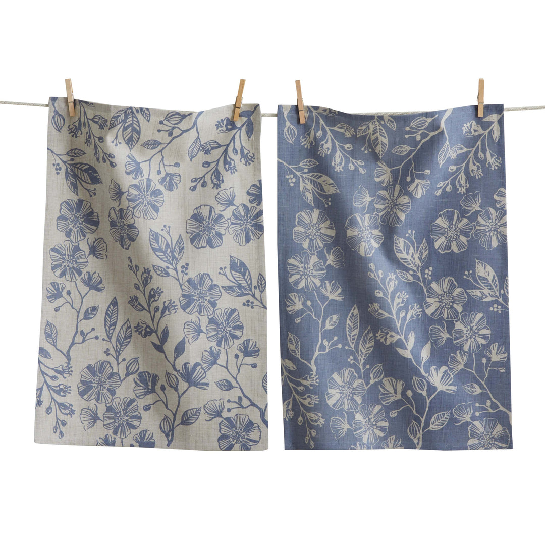 Two floral-patterned cloths hanging on a line against a white background