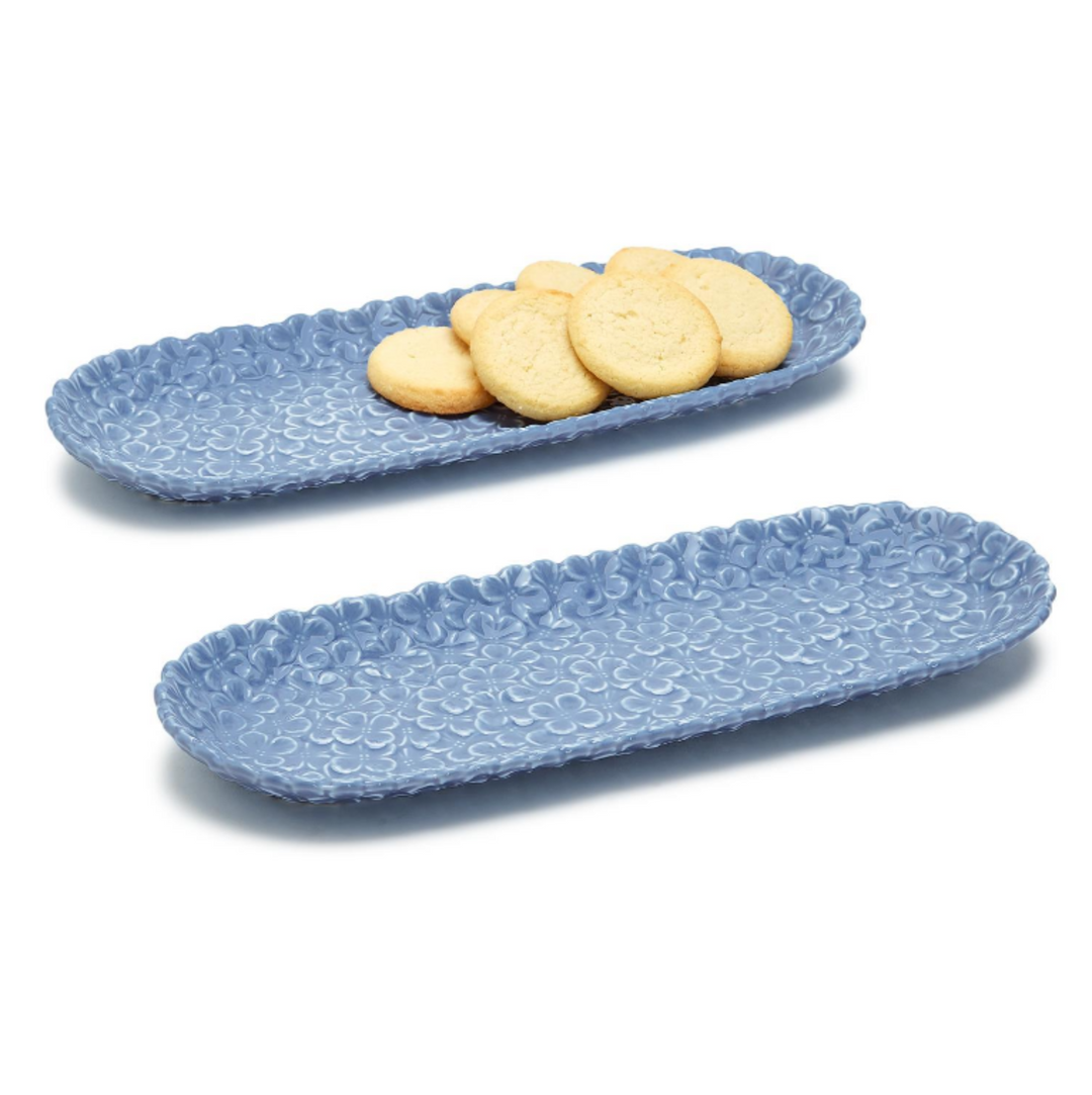 Two blue textured ceramic trays with cookies on a white background