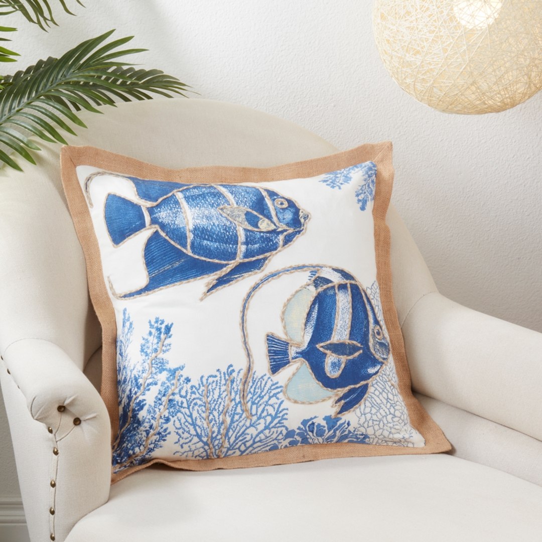 Decorative pillow with blue fish design on a white armchair