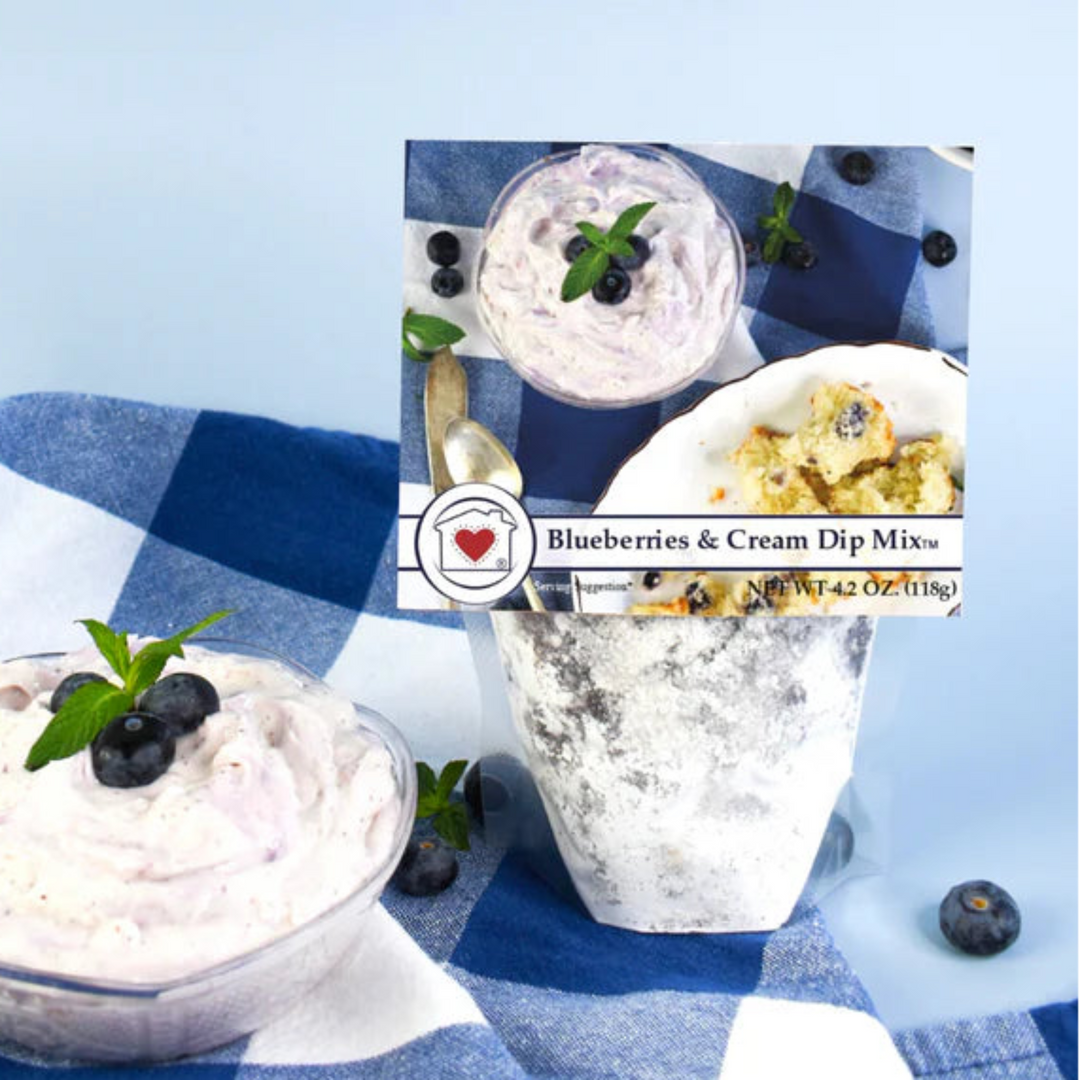 Two bowls of blueberries and cream dip with a package labeled 'Blueberries & Cream Dip Mix' on a blue and white checkered cloth.