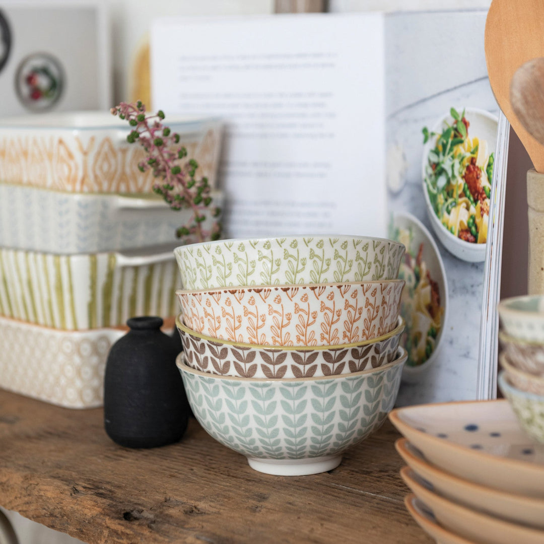 Stacked ceramic bowls with various patterns on a wooden surface.