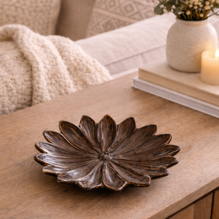 Decorative stoneware flower bowl on a wooden coffee table with a cozy living room setting.