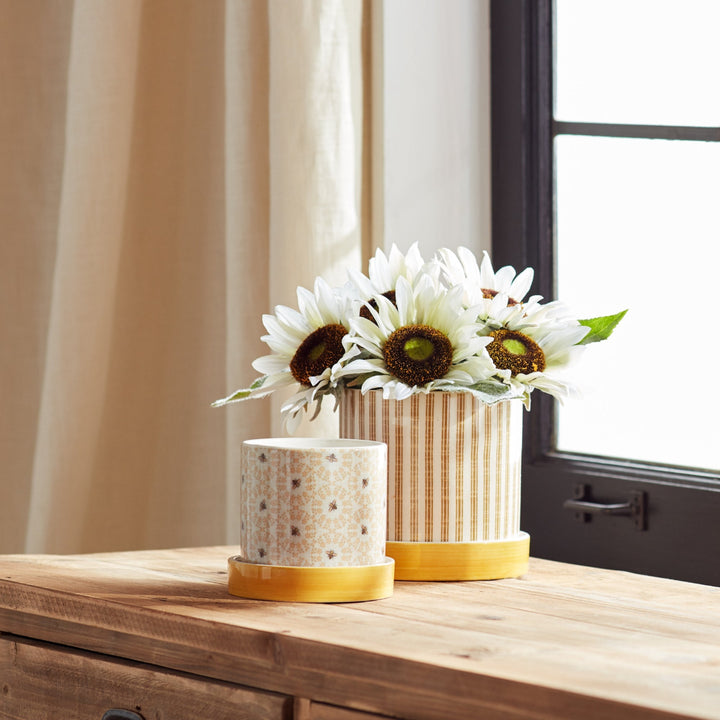 Two decorative vases with sunflower arrangements on a wooden surface.