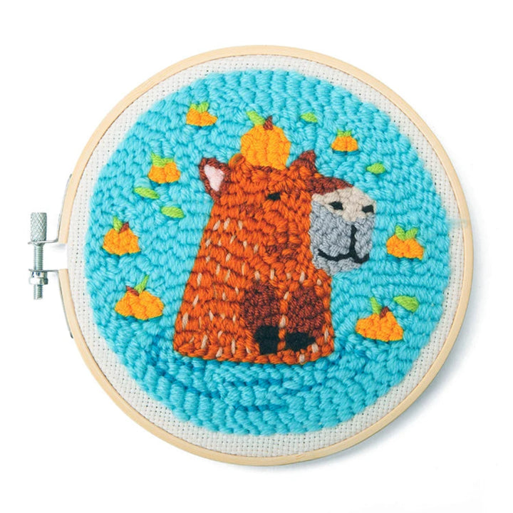 Embroidery hoop with a llama and pumpkin design on a blue background