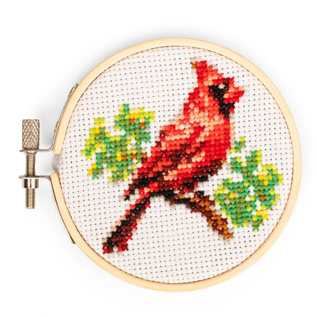 Cross-stitched red cardinal bird in an embroidery hoop on a white background