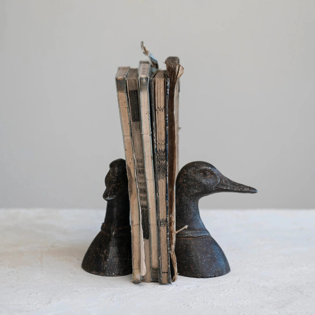 Bookend shaped like a duck and horse holding books on a white surface with a light gray background