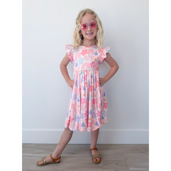 Young girl wearing a colorful dress with patterns on a plain background