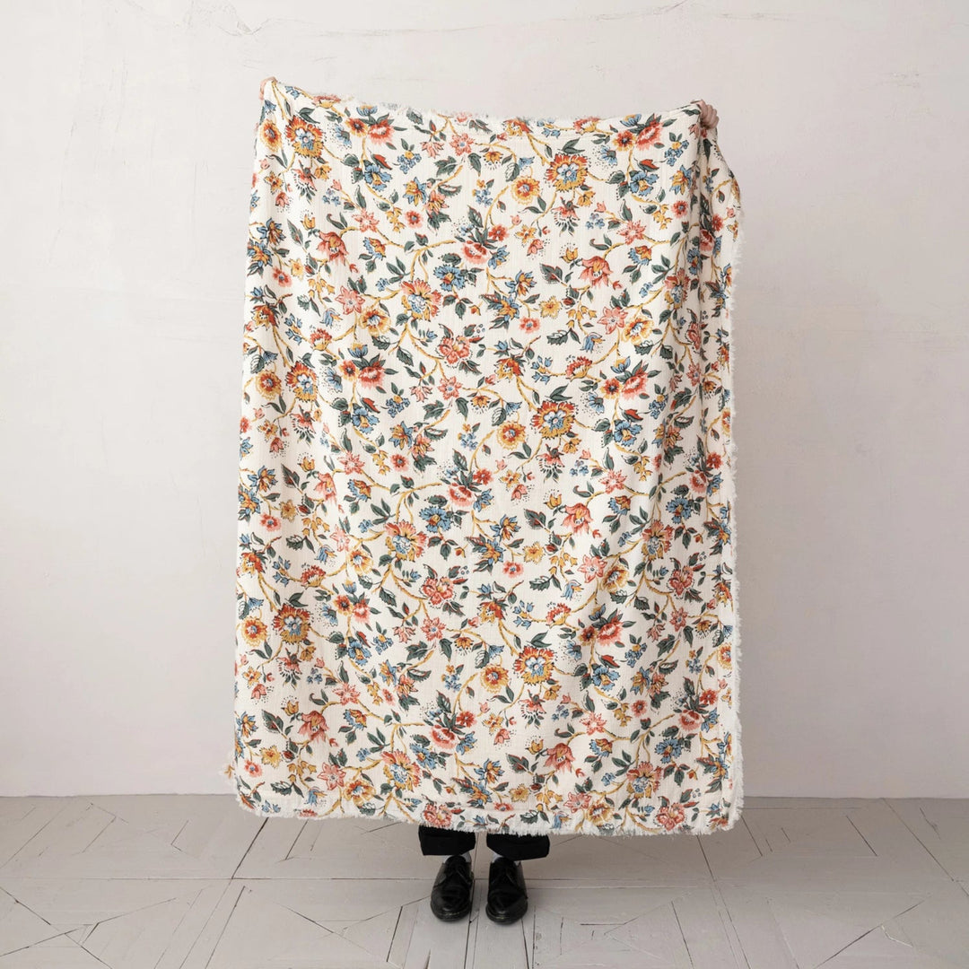 Floral patterned blanket draped over a person against a white background