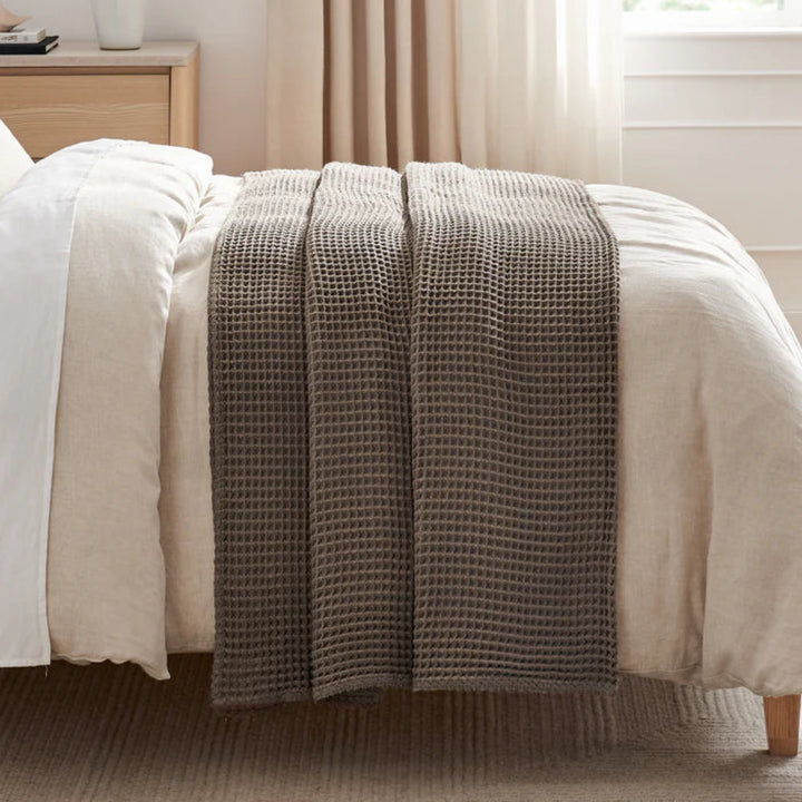 Brown textured throw blanket on a bed in a bedroom setting