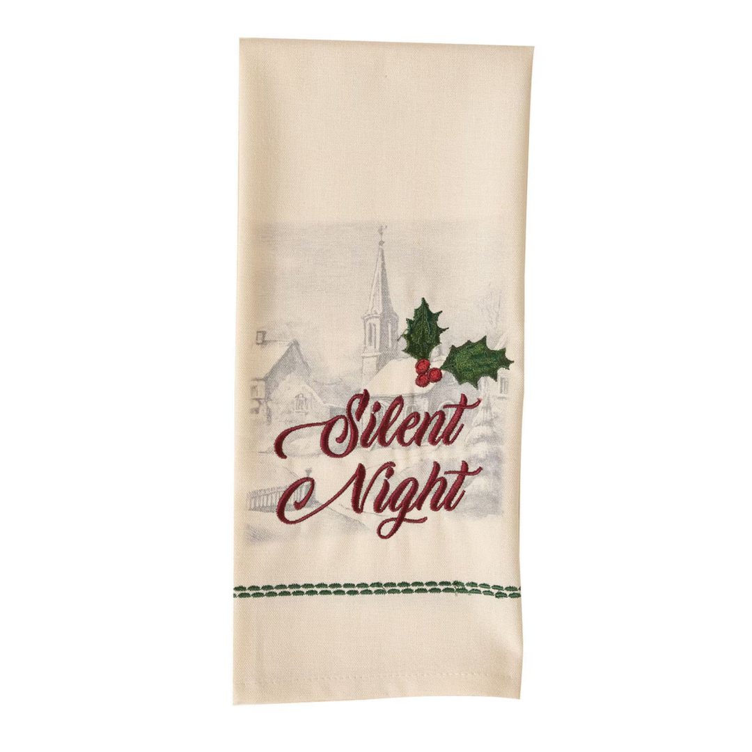 An off-white cotton tea towel with a Christmas design featuring the embroidered text 'Silent Night' in dark red, green holly leaves, a faint winter village scene, and a green stitched border at the bottom.