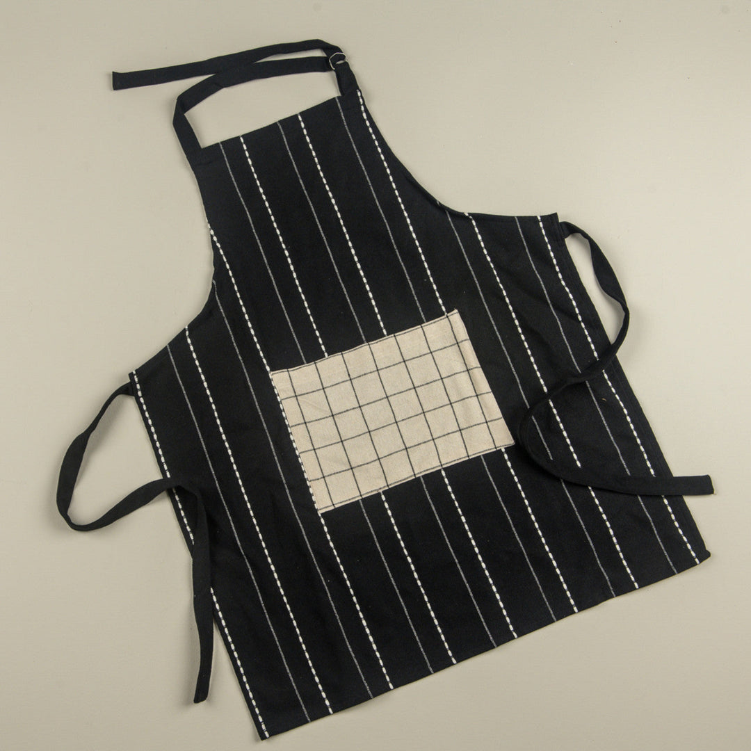 Black apron with white stripes and a grid-patterned pocket on a beige background