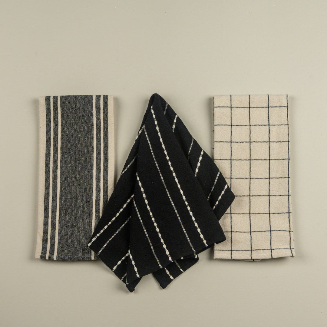 Three kitchen towels with different patterns on a beige background