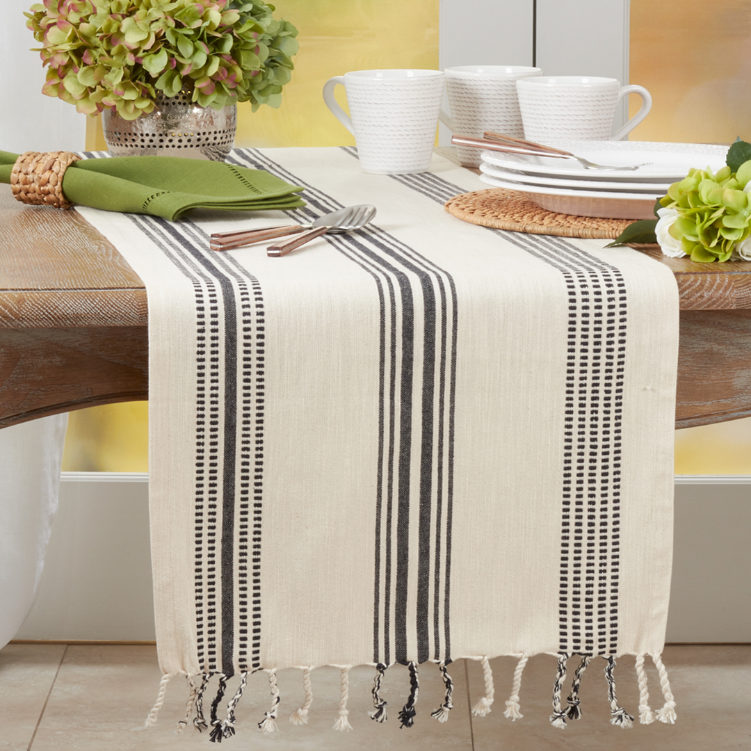 Table setting with a striped table runner, white plates, and green flowers.