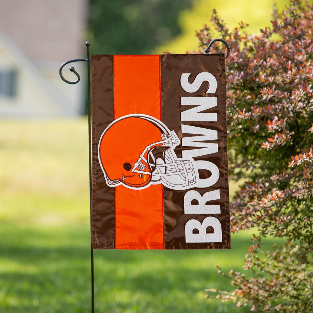 Cleveland Browns garden flag with orange and brown stripes in a yard setting