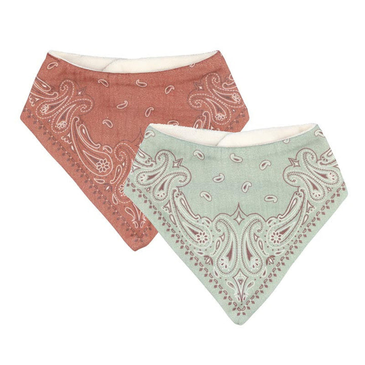 Two triangular bandana bibs with paisley patterns, one in terracotta orange and one in sage green, both with a cream lining, shown on a plain white background.