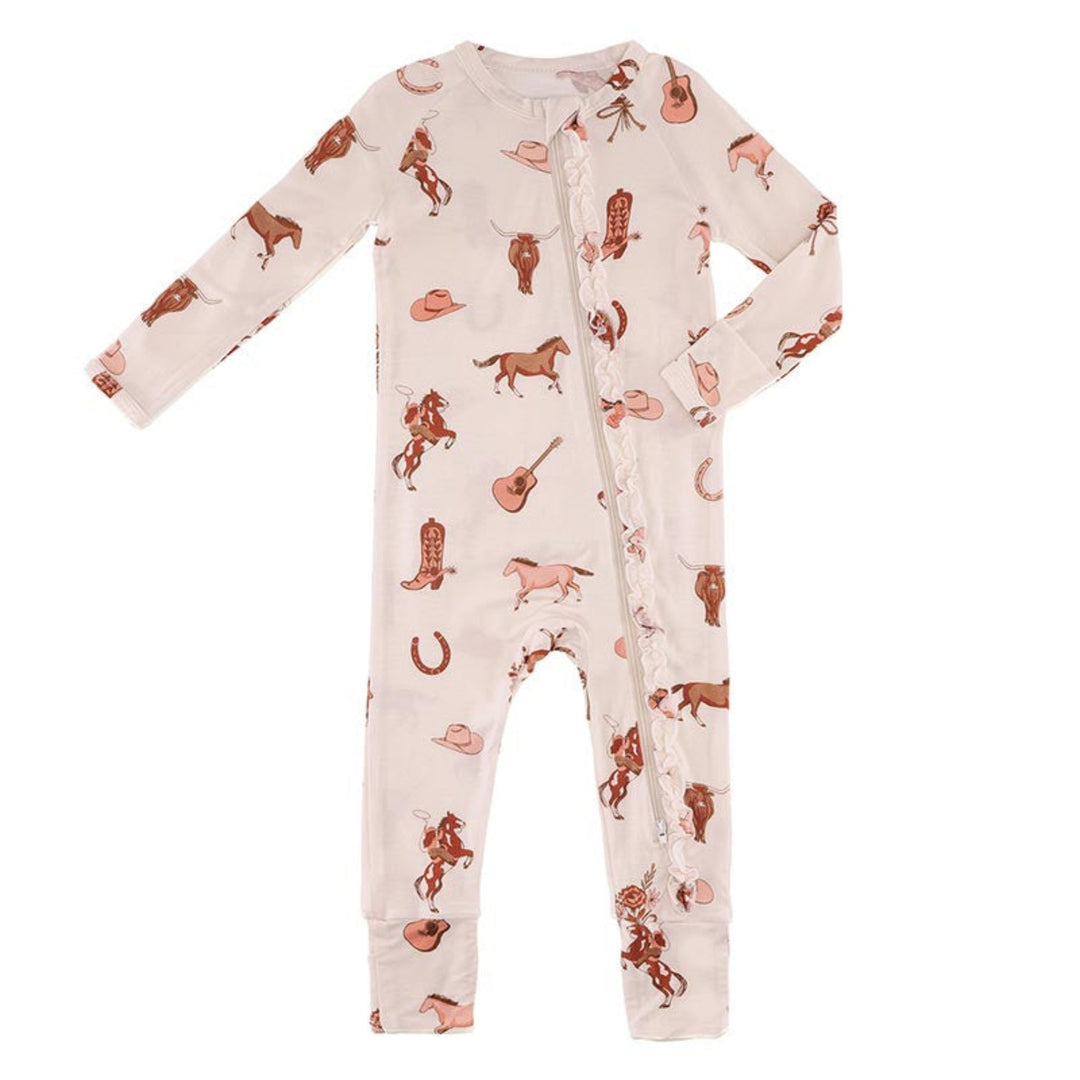 A baby long-sleeve footless one-piece pajama with a western-themed print, featuring cowboy boots, hats, guitars, and horses on a light pink background.
