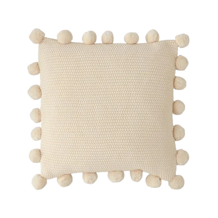 Beige pillow with pom-pom details on a white background