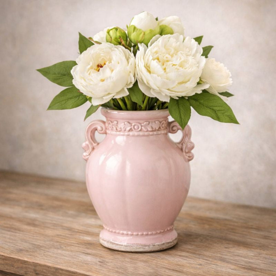 Pink vase with white flowers on a wooden surface