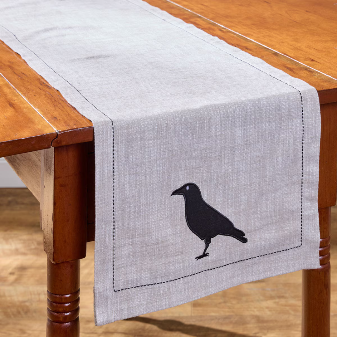 Gray table runner with a black bird silhouette on a wooden table.