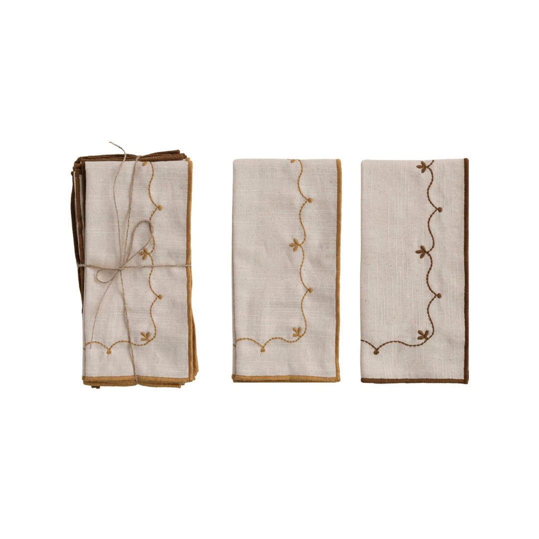 Set of three embroidered napkins with decorative patterns on a white background