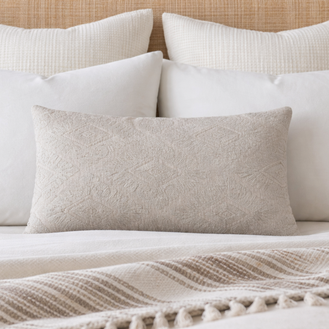 Neatly arranged pillows on a bed with a textured headboard