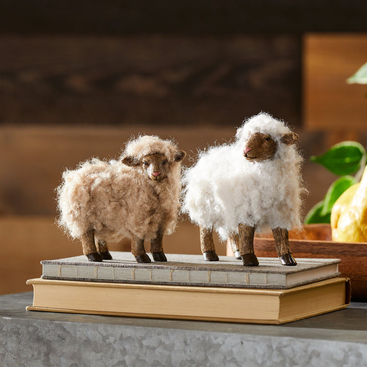 Two fluffy sheep figurines on a stack of books with a blurred background