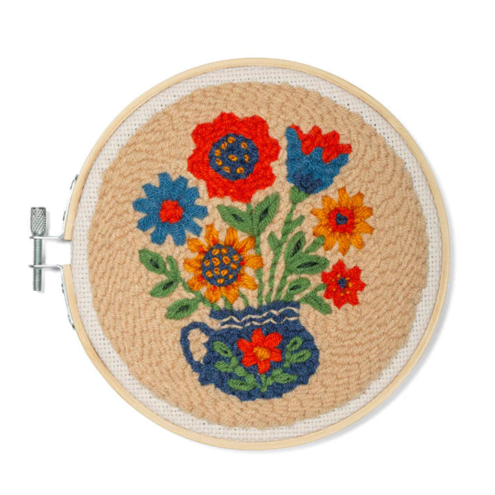 Embroidery hoop with colorful floral design on a beige background