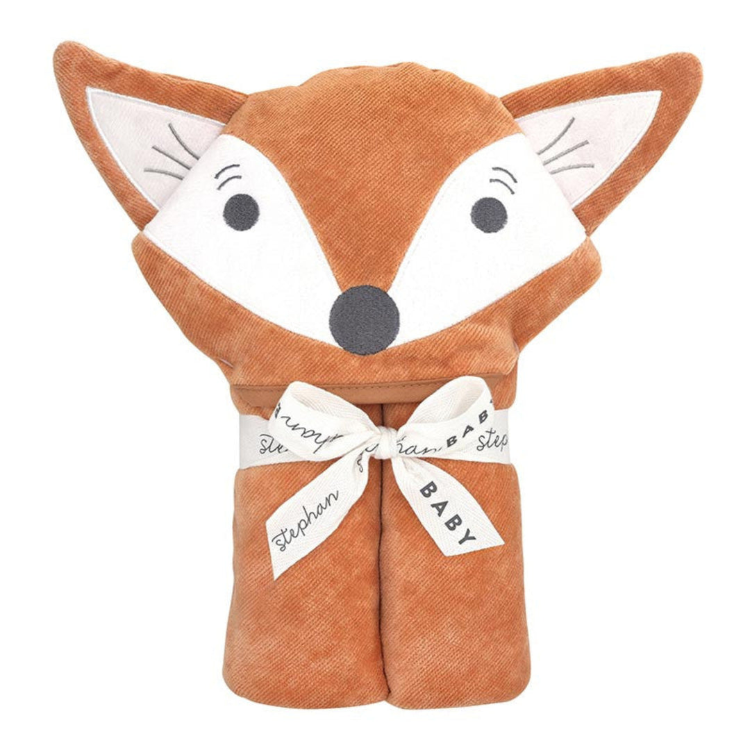 A plush hooded baby blanket shaped like a fox head, in warm rust-brown and white fabric, tied with a white ribbon printed with names and the word BABY, on a plain white background.