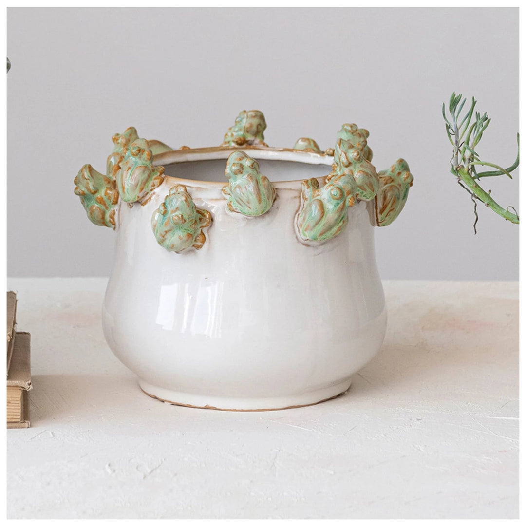 Decorative ceramic pot with green decorative elements on a white surface