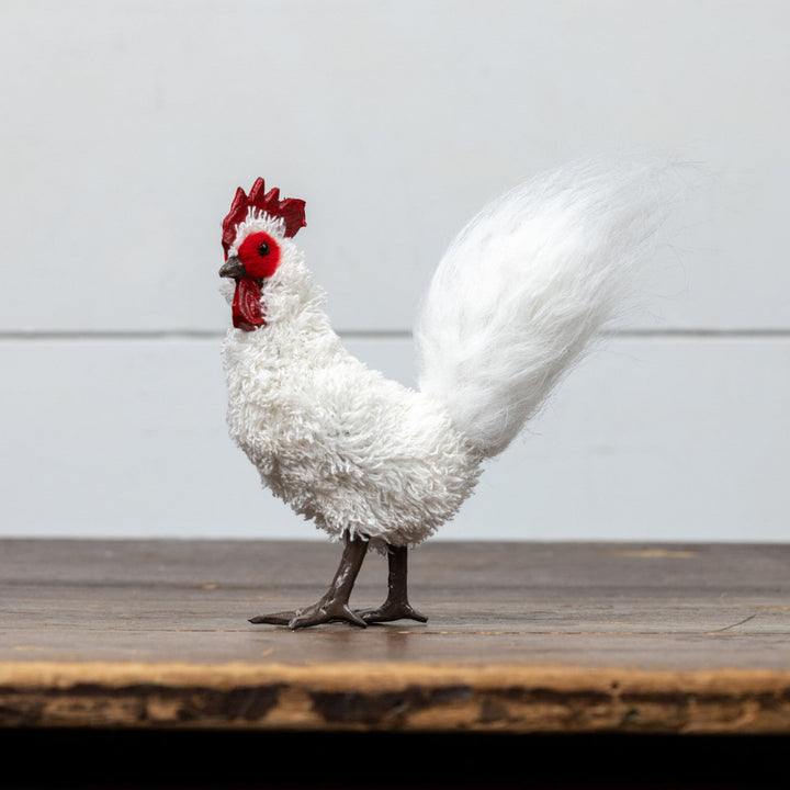 White rooster figurine with red comb on a wooden surface