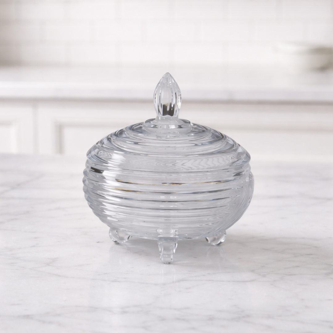 Clear glass candy dish with ribbed design on a marble surface