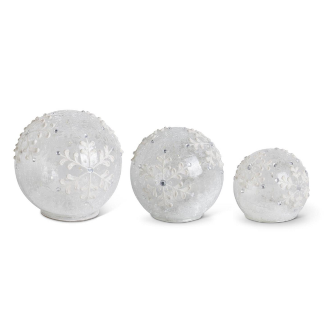 Three frosted glass Christmas ornaments in different sizes, decorated with embossed snowflakes and small rhinestones, displayed on a clean white background.